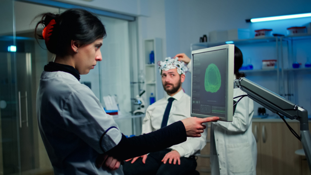 woman-researcher-looking-monitor-analysing-brain-scan-while-coworker-discussing-with-patient-background-about-side-effects_optimized_2000