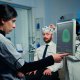 woman-researcher-looking-monitor-analysing-brain-scan-while-coworker-discussing-with-patient-background-about-side-effects_optimized_2000