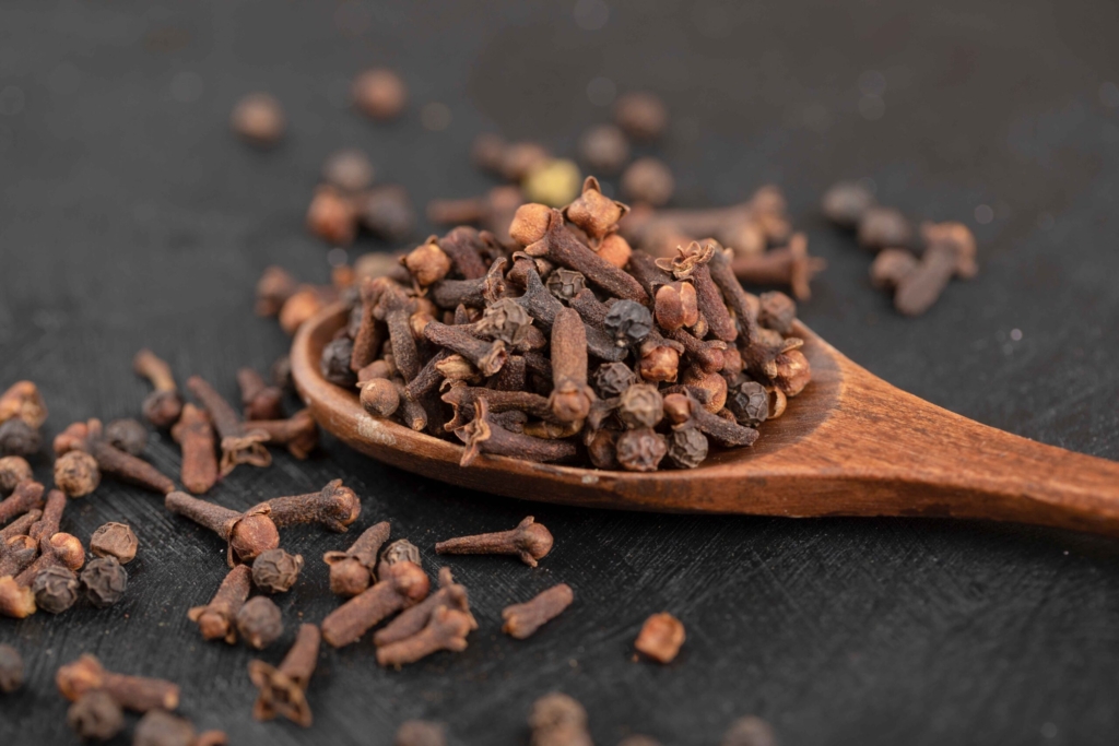 pile-dried-natural-cloves-with-wooden-spoon-black-surface_11zon