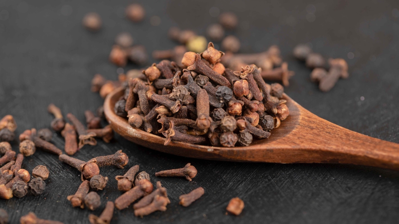pile-dried-natural-cloves-with-wooden-spoon-black-surface_11zon