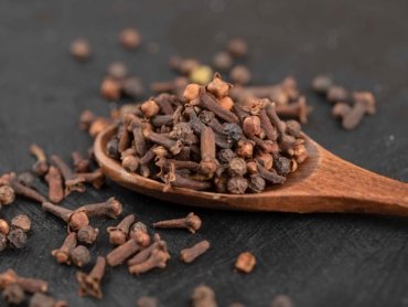 pile-dried-natural-cloves-with-wooden-spoon-black-surface_11zon