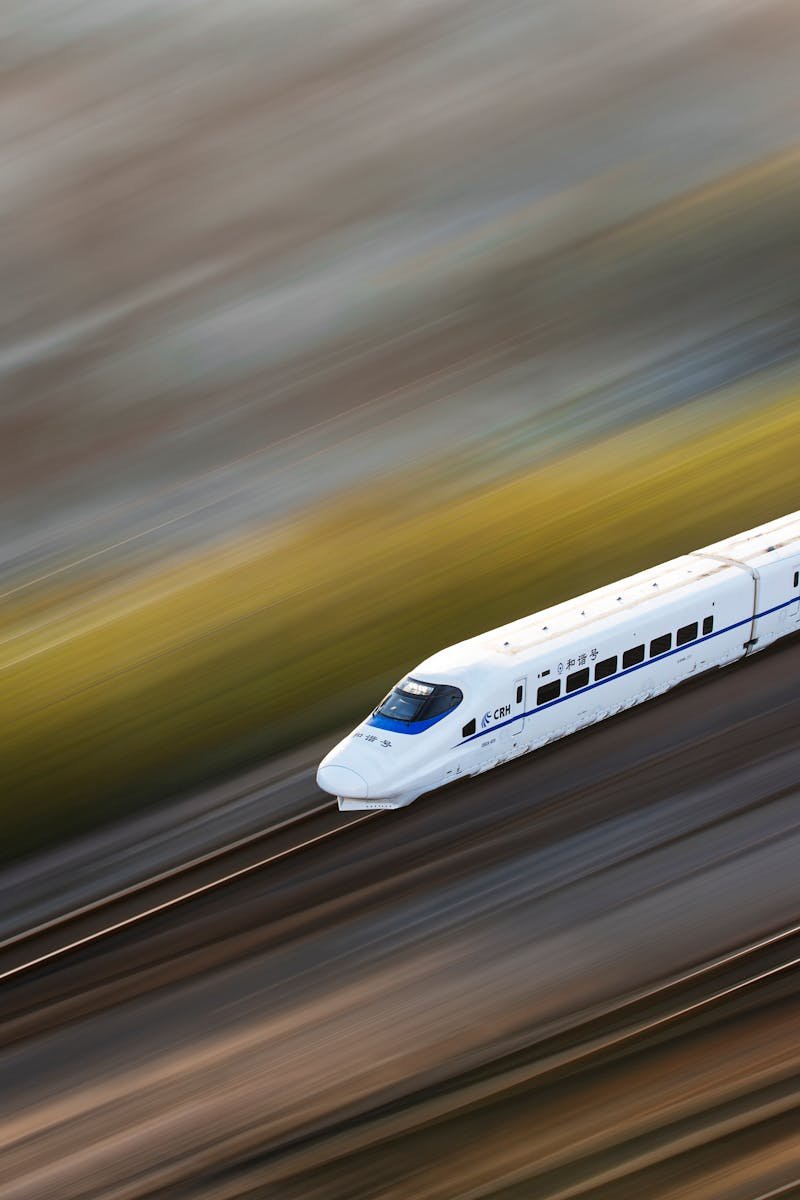 A sleek white high-speed train traveling at top speed, captured with a motion blur effect.