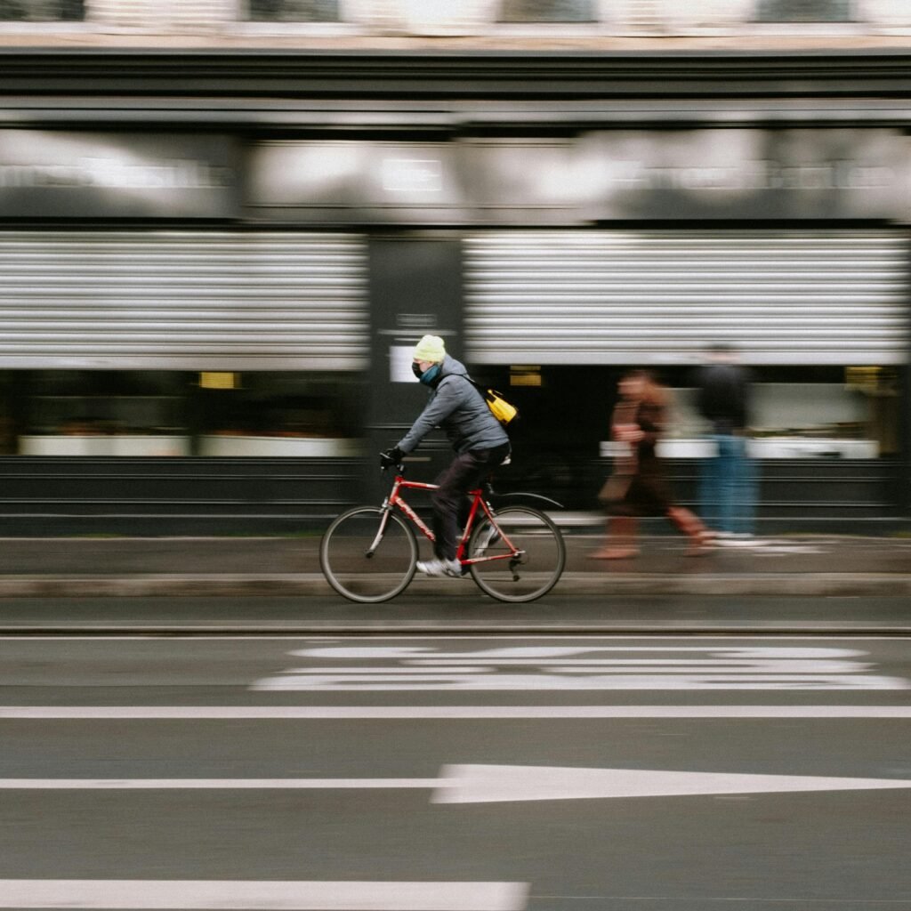 Blurry cyclist in winter jacket biking swiftly on a city street showcasing motion blur.