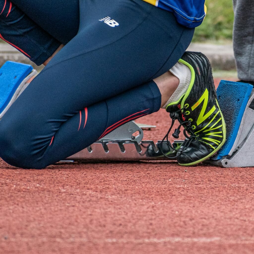 Close-up of a runner's legs ready to start a race, showcasing running shoes and starting block.