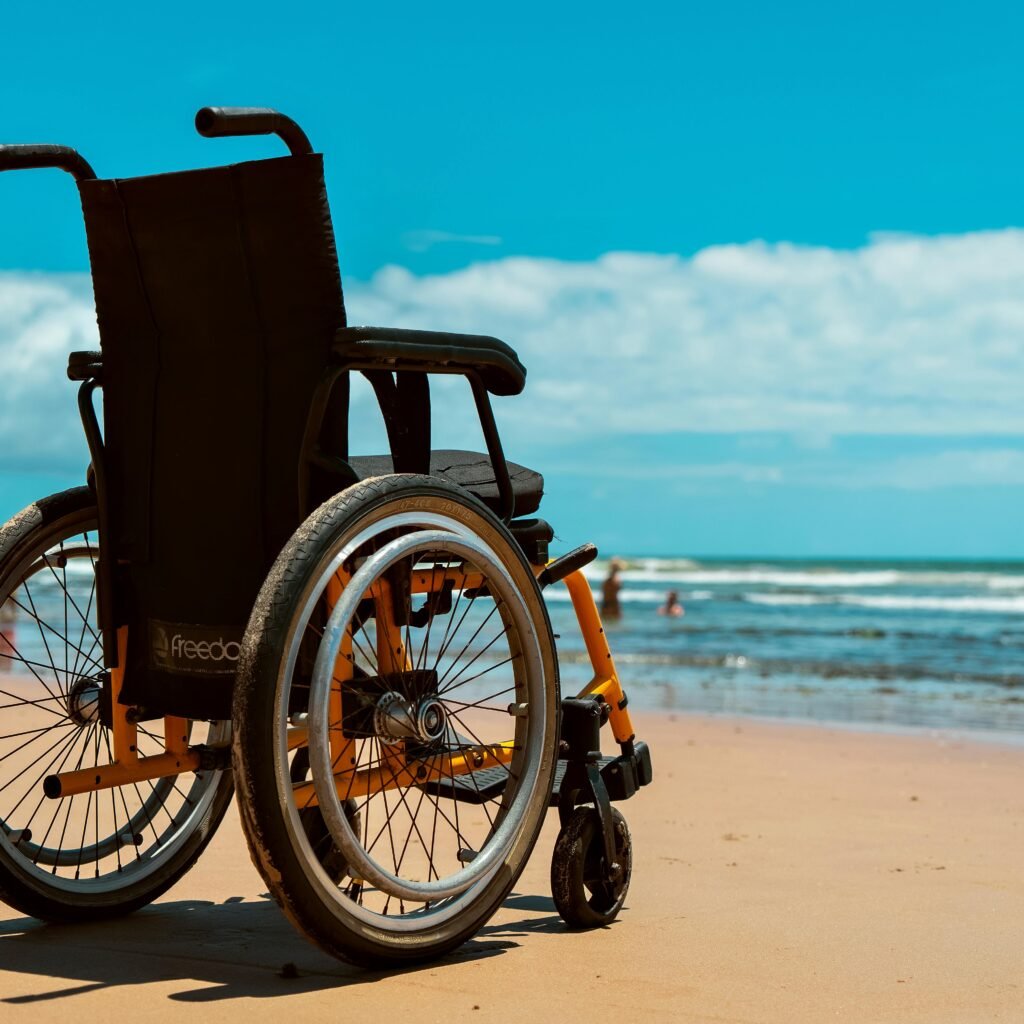 A wheelchair on a sandy beach overlooking the sea on a bright summer day.
