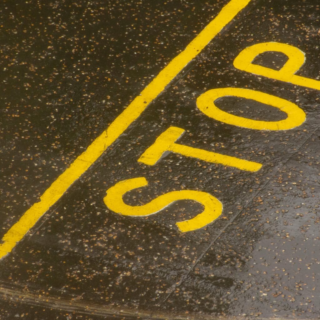 Rain-soaked road with a painted yellow STOP sign for traffic control.