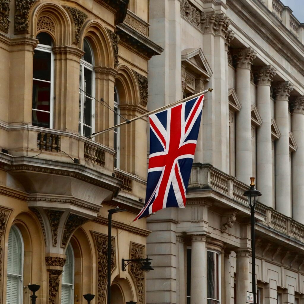 Union Jack flag flying on a historic London building facade.