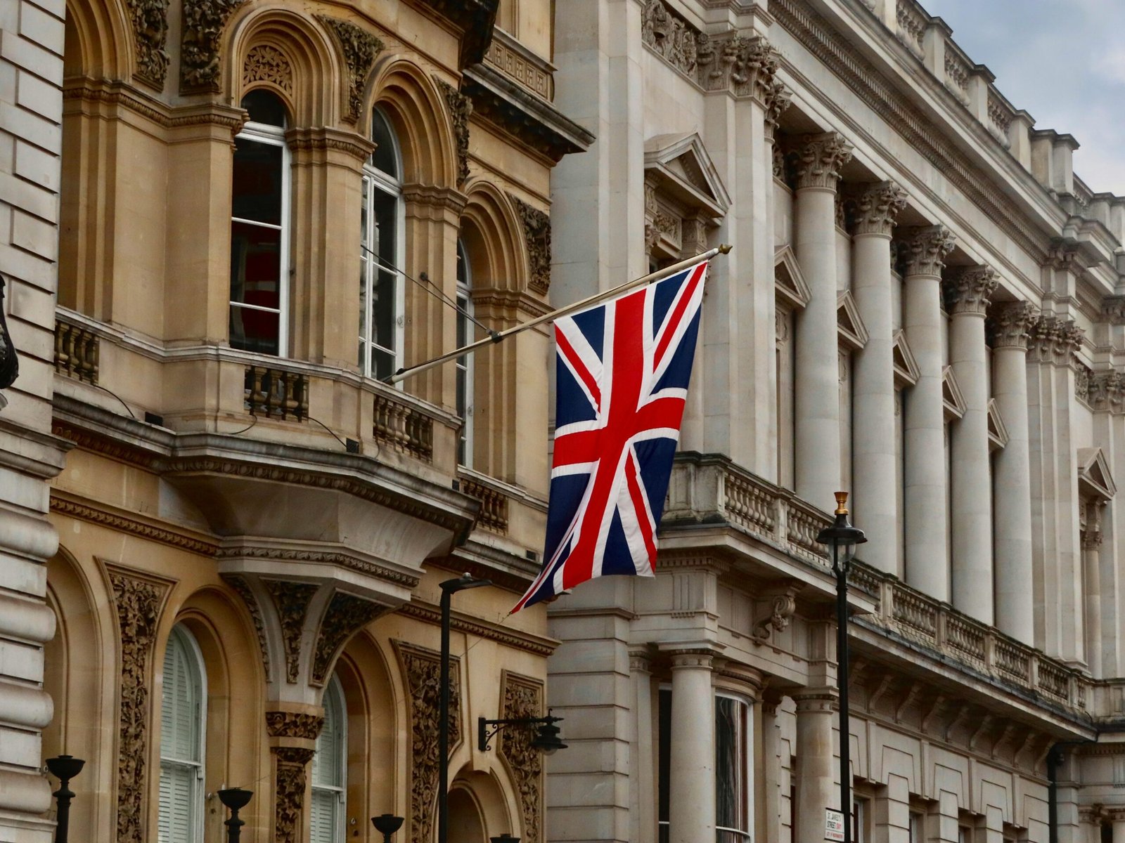 Union Jack flag flying on a historic London building facade.