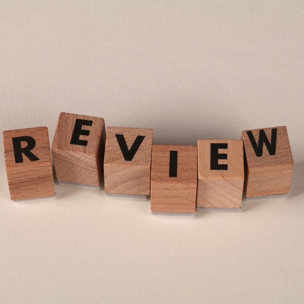 Wooden blocks with letters forming the word 'Review' on a soft pastel background.