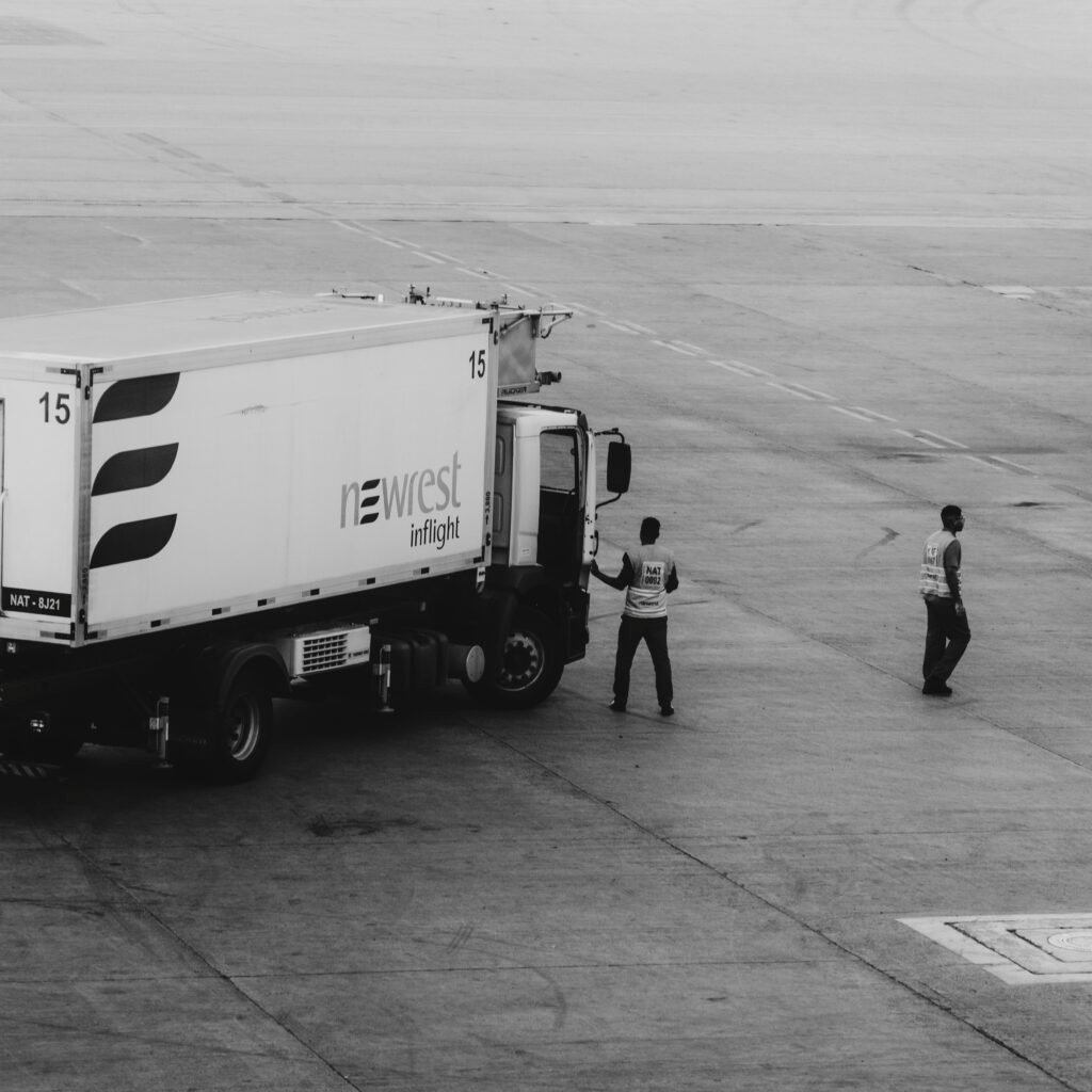 Black and white photo of a catering truck with crew on an airport tarmac.