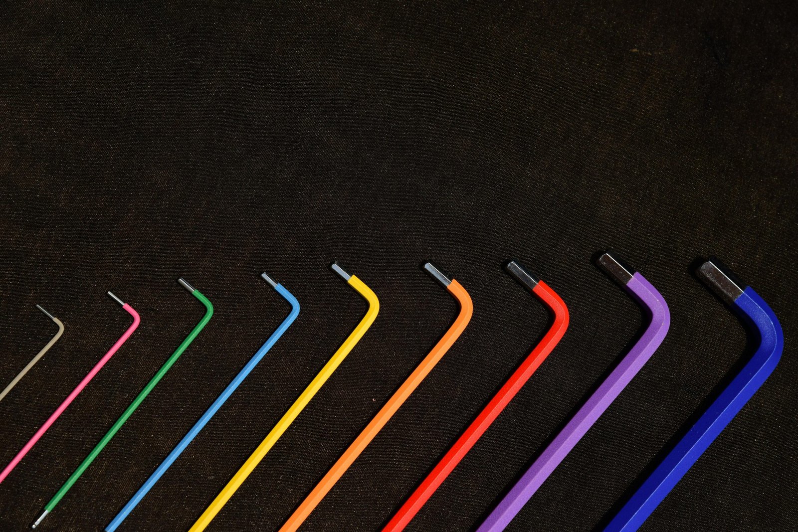 Vibrant set of hex keys in rainbow colors organized in a neat pattern on a dark backdrop.