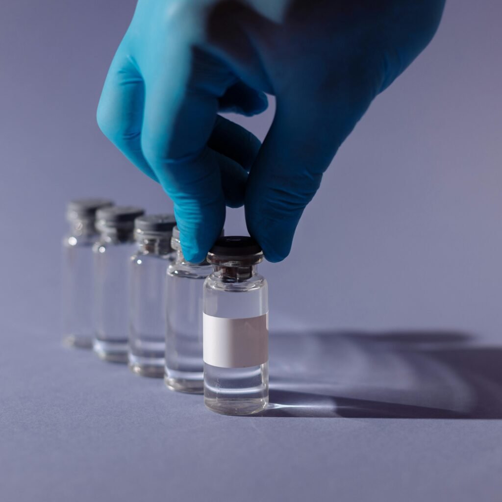Healthcare worker with gloves handling vaccine vials in a sterile environment.