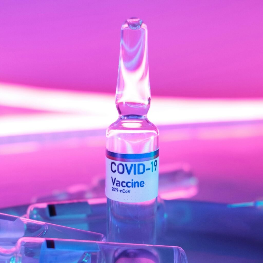 Ampoule with vaccine for injection for COVID 19 in laboratory in bright purple light