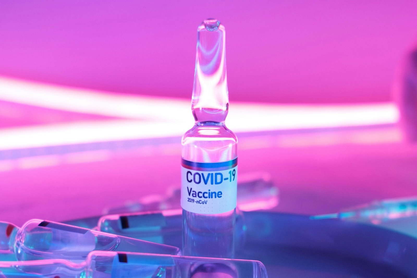 Ampoule with vaccine for injection for COVID 19 in laboratory in bright purple light