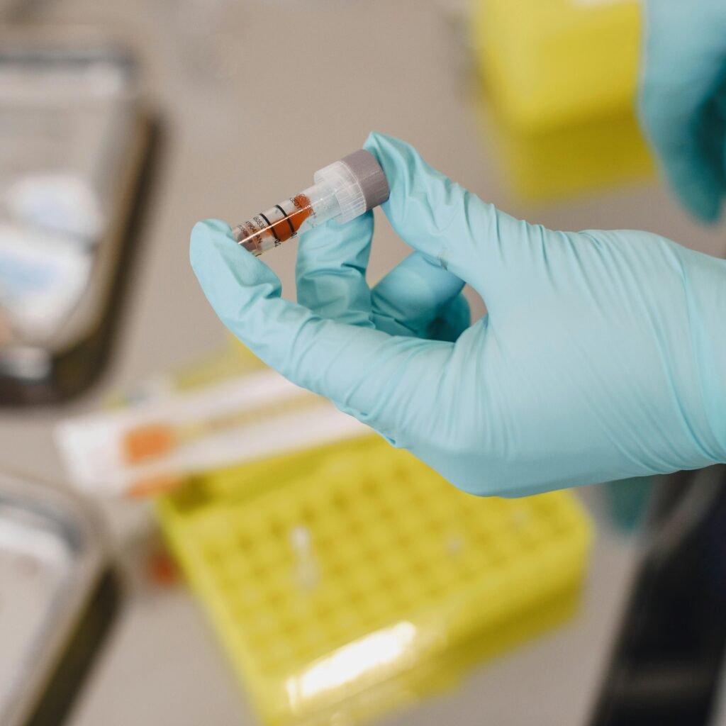 Close-up of a scientist's hand holding a test tube with protective gloves in a lab.