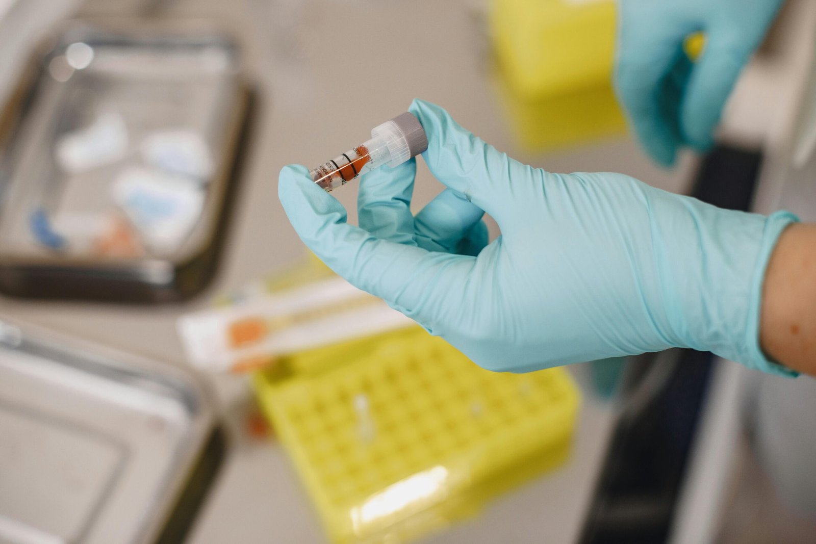 Close-up of a scientist's hand holding a test tube with protective gloves in a lab.