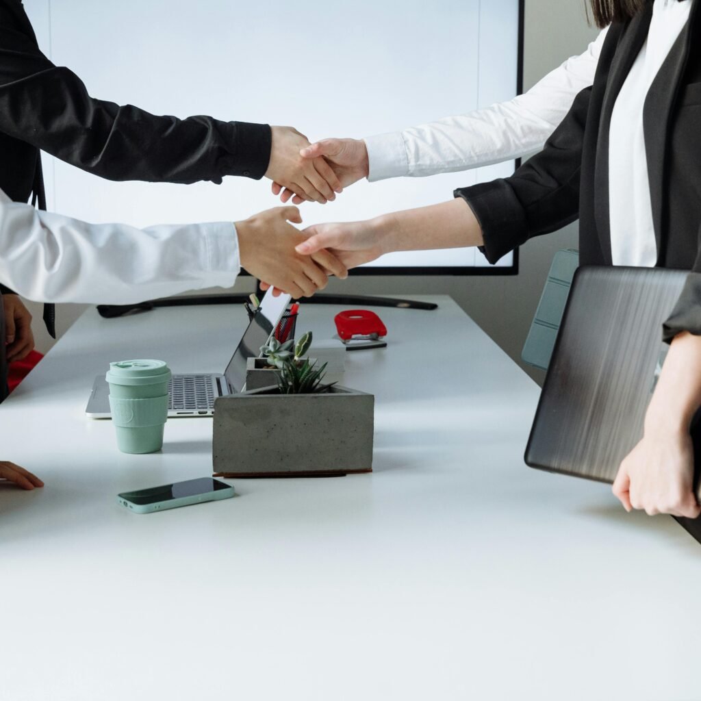 Professionals sealing a deal with a handshake across a conference table during a business meeting.