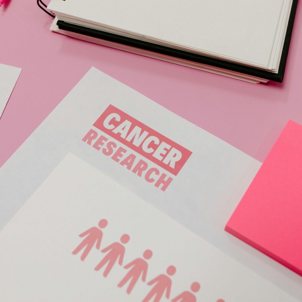 Assorted cancer research materials laid on a pink desk. Professional workspace.