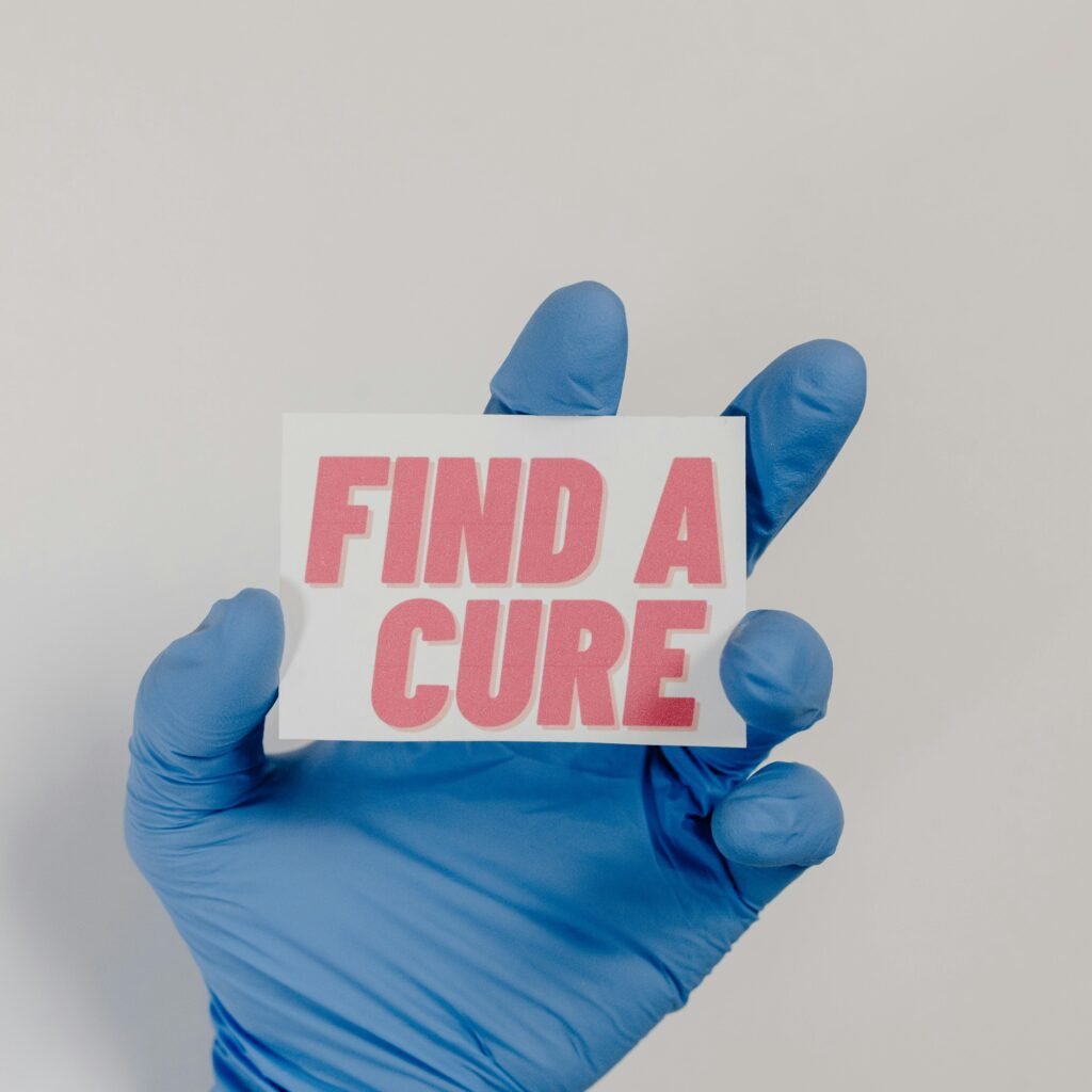 A blue-gloved hand holds a card with 'Find a Cure' message, symbolizing cancer awareness.