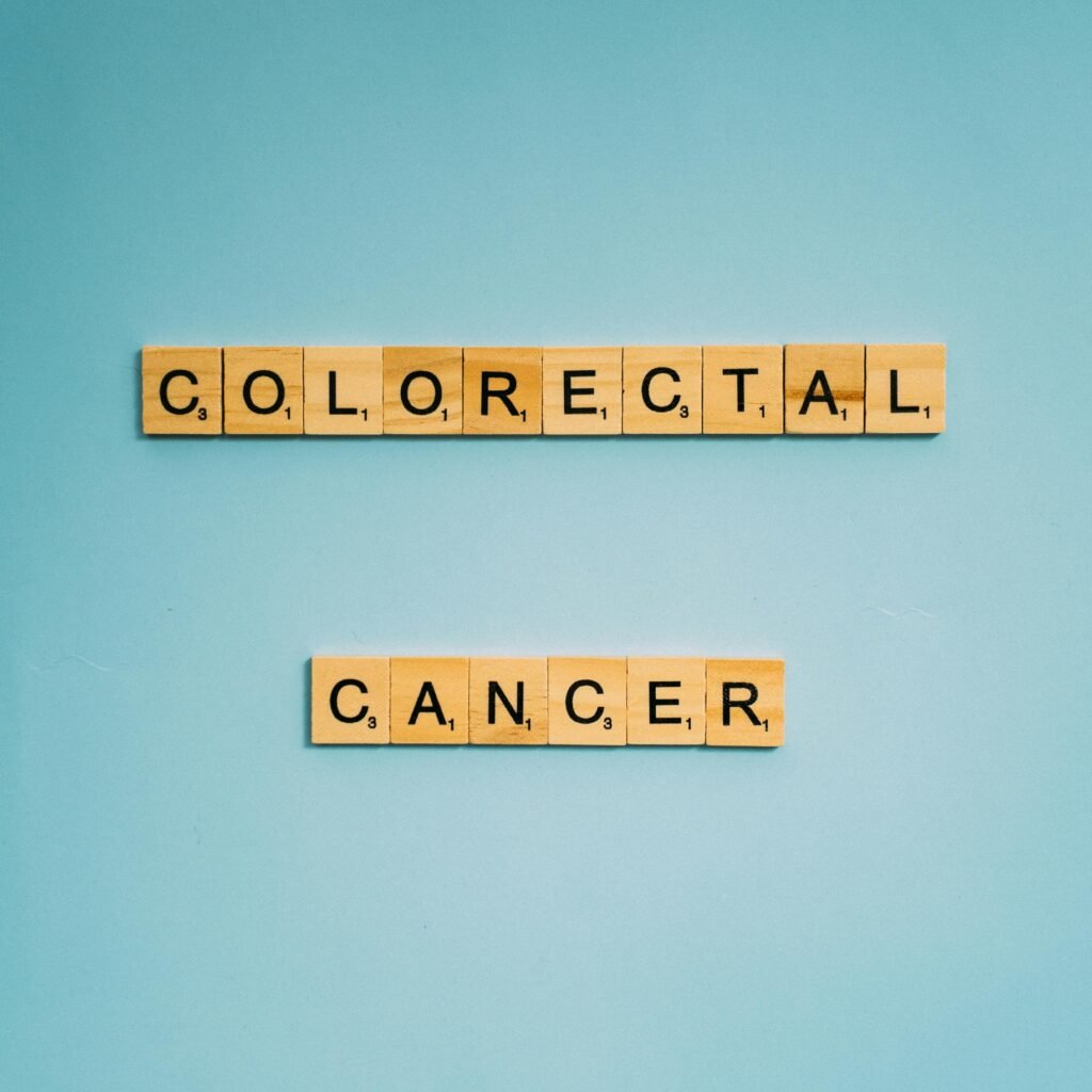 Scrabble tiles spell 'Colorectal Cancer' on a light blue background for cancer awareness.