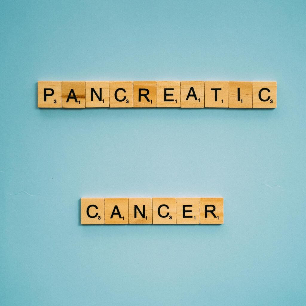 Wooden tiles spelling pancreatic cancer on blue. Health awareness concept.