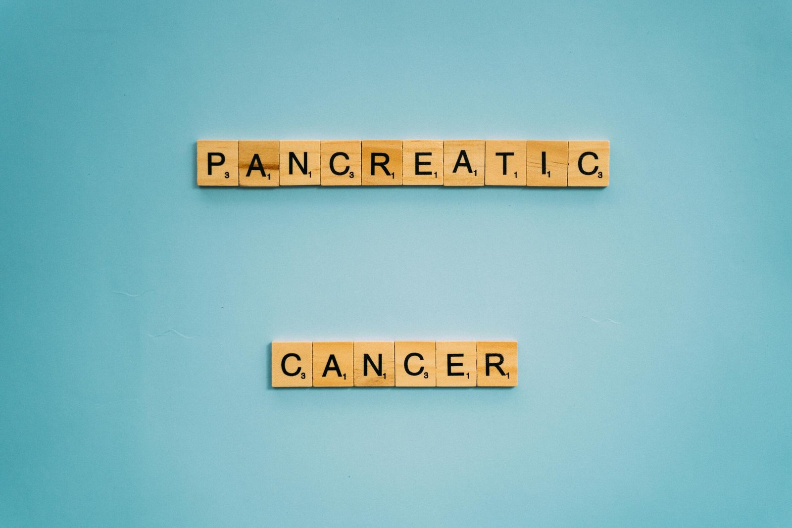 Wooden tiles spelling pancreatic cancer on blue. Health awareness concept.
