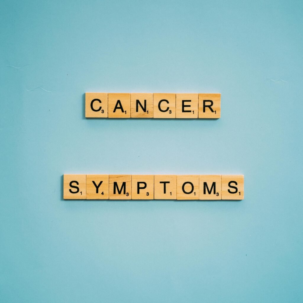 Scrabble tiles spelling 'cancer symptoms' on a blue background, emphasizing awareness.