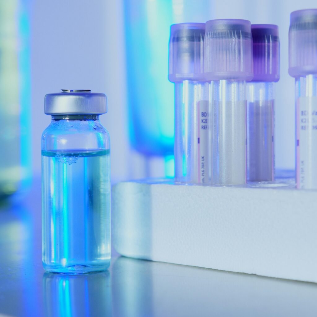 Vials and test tubes with blue liquid in a laboratory setting under fluorescent light.