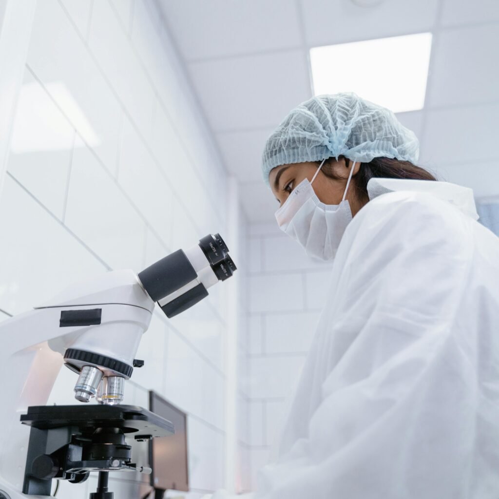 A scientist in protective gear uses a microscope in a modern laboratory setting.