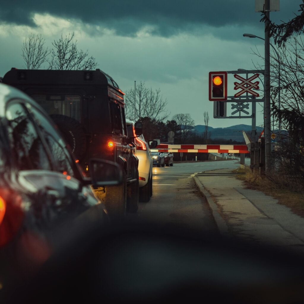 A line of cars waiting at a railway crossing during the night, showcasing urban transportation.