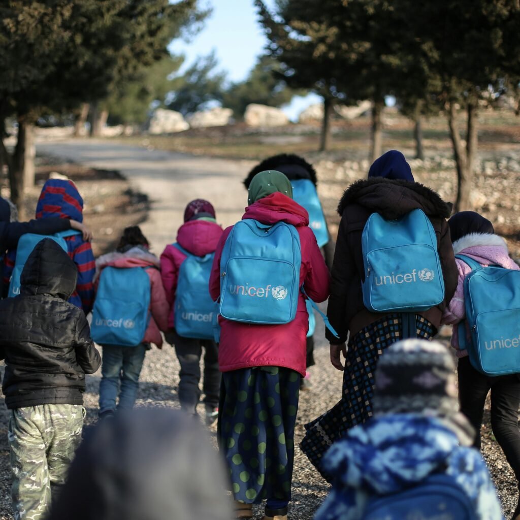 A group of children with UNICEF backpacks walking on a dirt road in rural Syria.