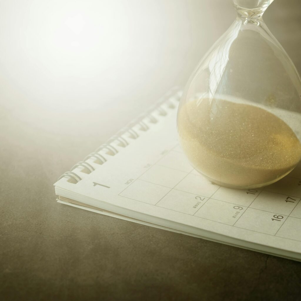 An hourglass on a calendar captures the essence of time management and urgency.