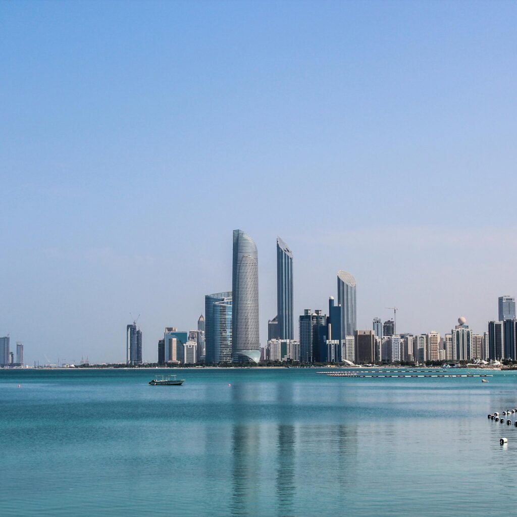 Stunning view of the Abu Dhabi skyline reflecting in the calm Gulf waters on a sunny day.