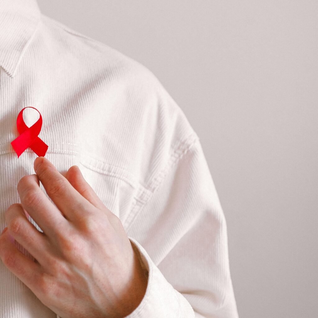 Close-up of a red ribbon on a white shirt symbolizing AIDS awareness and support.