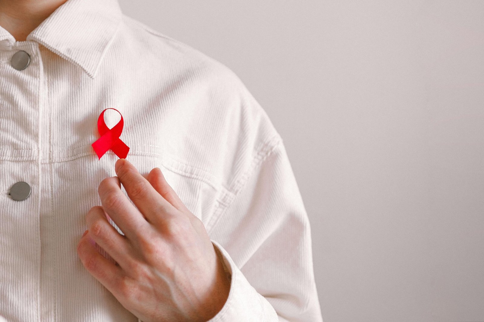 Close-up of a red ribbon on a white shirt symbolizing AIDS awareness and support.