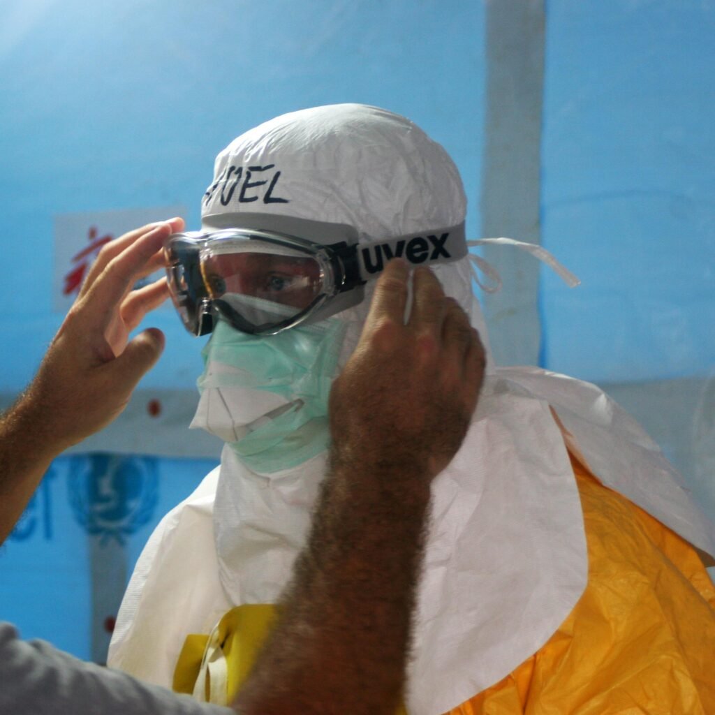 Healthcare worker puts on PPE gear in a medical facility for safety and protection.