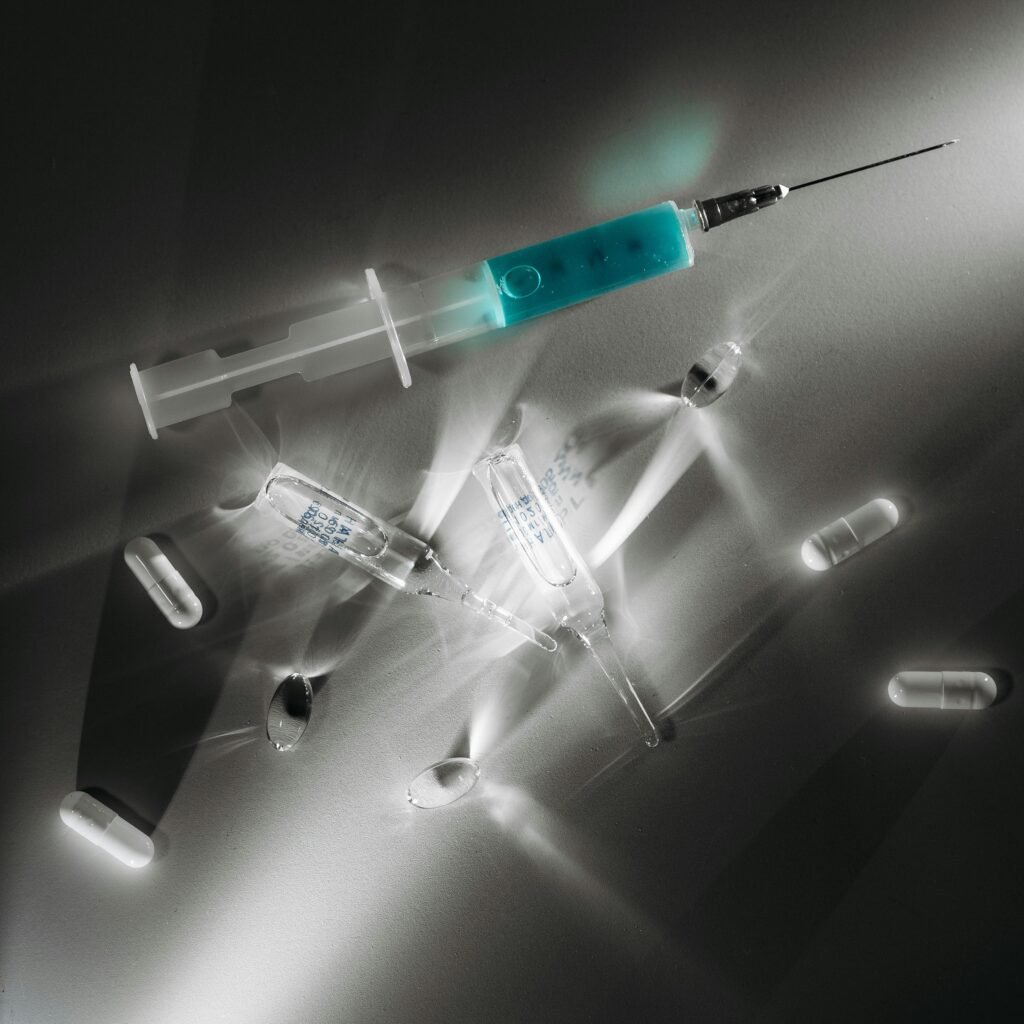 High contrast image of medical supplies, including a syringe and capsules, in a monochrome setting.