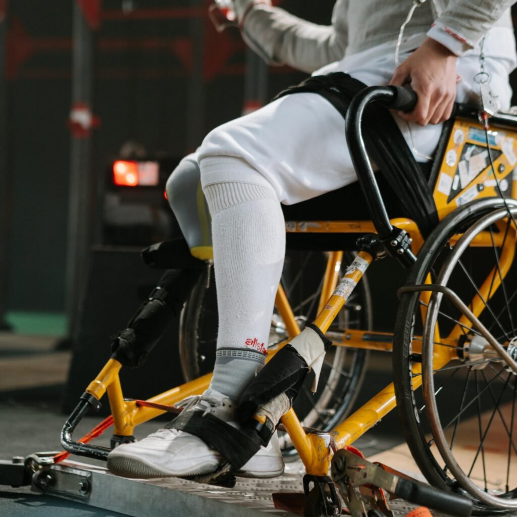 Focused athlete in wheelchair fencing gear, showcasing strength and determination.