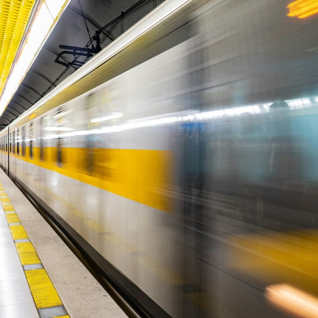 Blurred motion of a train speeding through a vibrant subway platform with commuters.