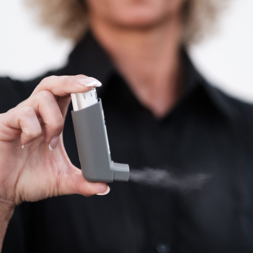 Person holding and using an inhaler, showcasing healthcare and respiratory care indoors.