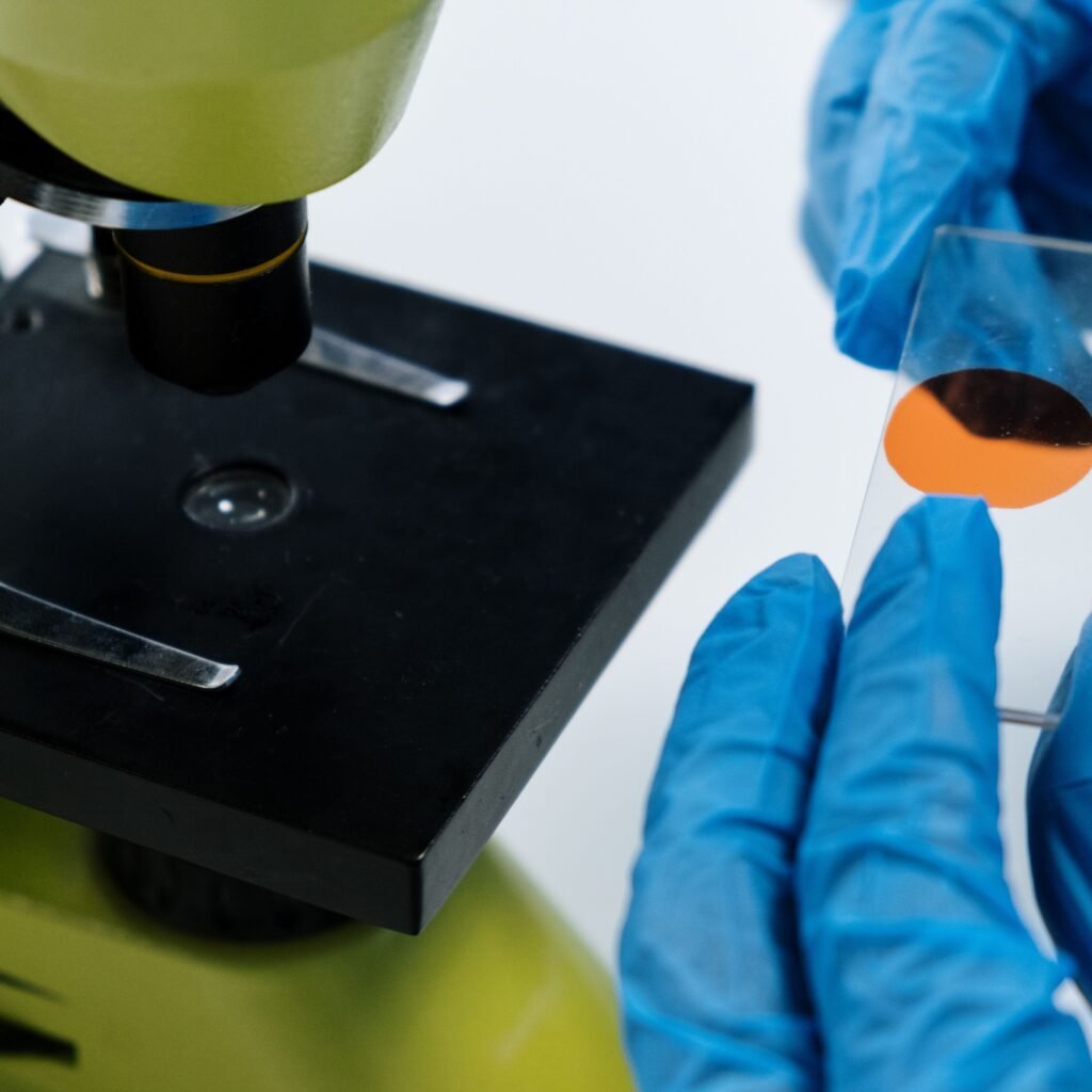 Close-up of a scientist handling a microscope slide with blue latex gloves, preparing for analysis.
