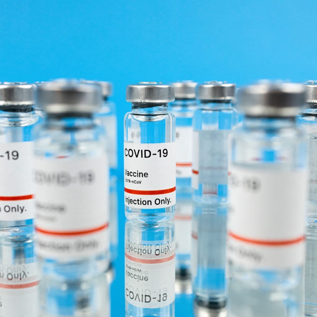 Close-up of COVID-19 vaccine vials on a reflective surface against a blue background.