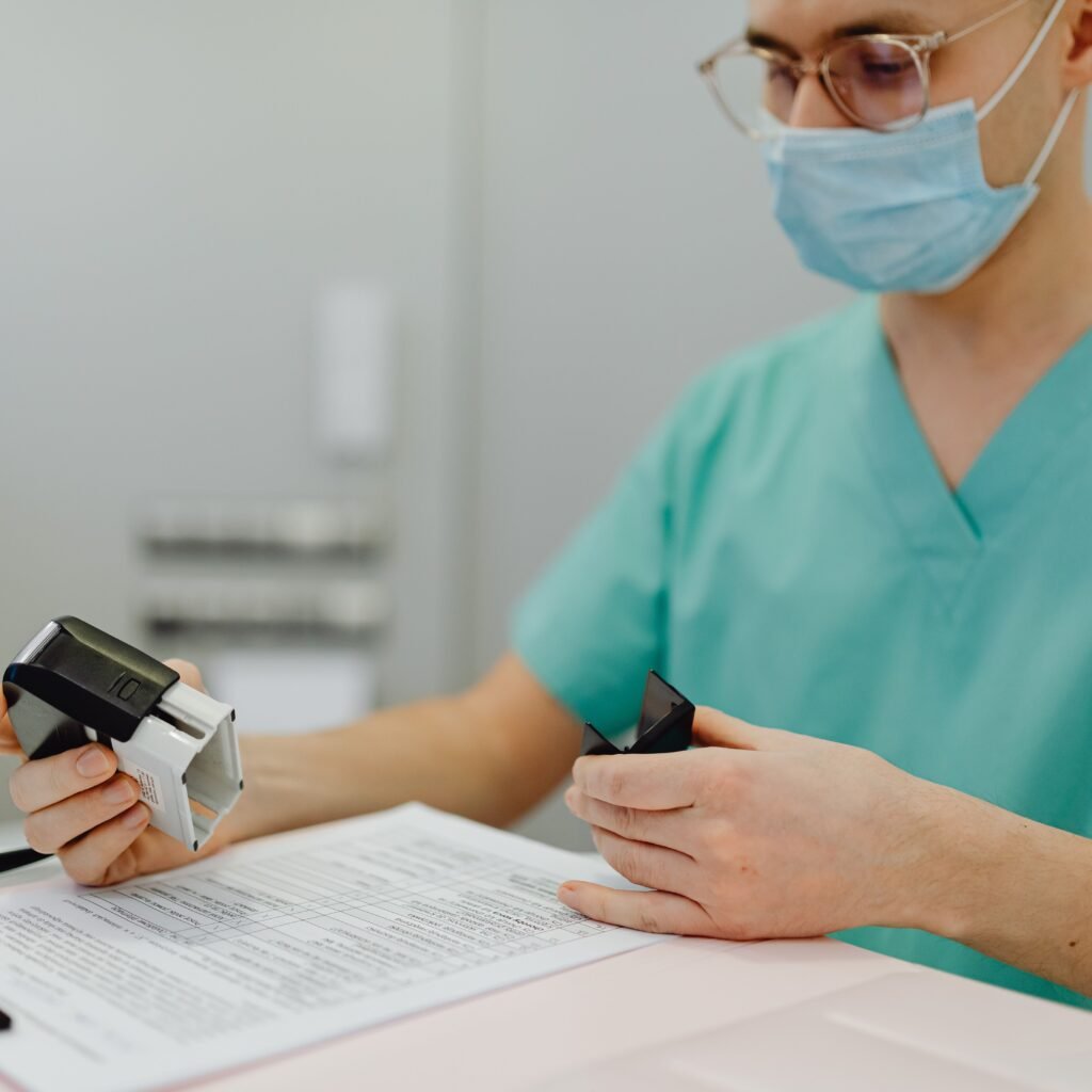 Healthcare worker in scrubs reviewing patient files with a stamp and clipboard.