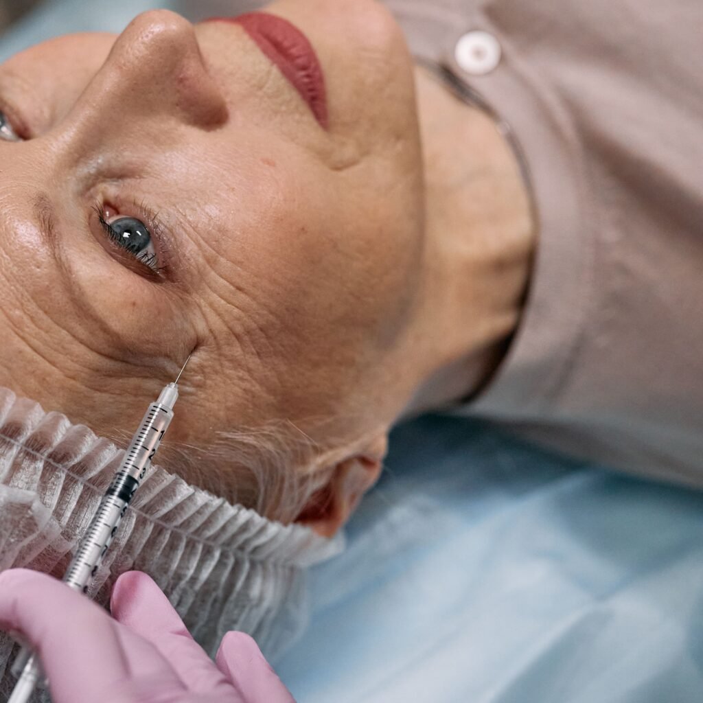 A senior woman undergoes a cosmetic injection procedure in a medical facility.