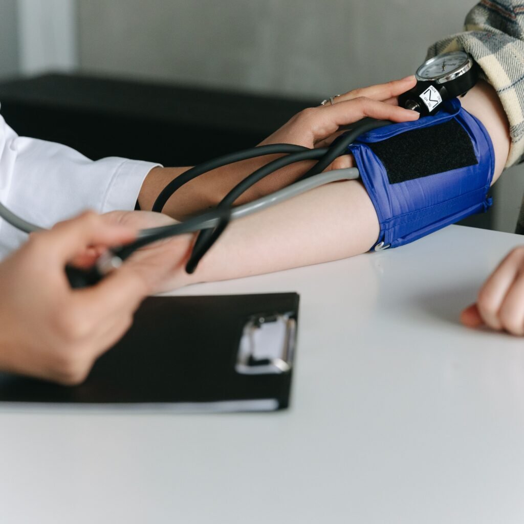 A healthcare worker uses a sphygmomanometer to check a patient's blood pressure in a medical office.