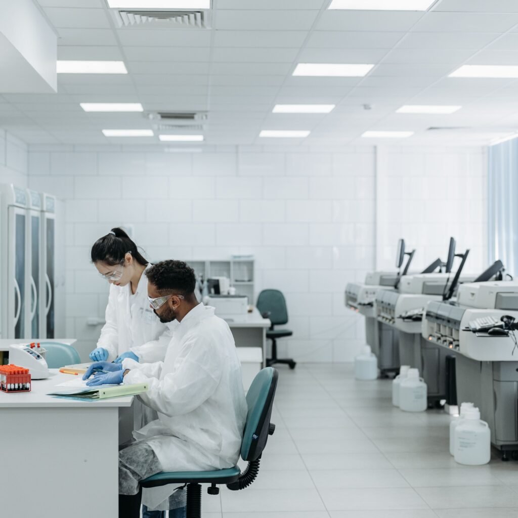 Scientists in a laboratory analyzing samples with advanced equipment and protective gear.