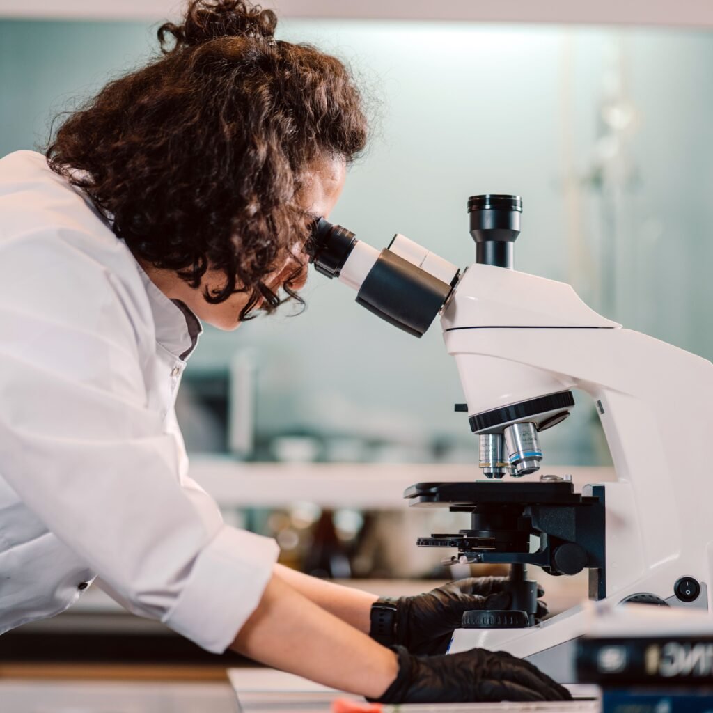 A woman scientist using a microscope in a laboratory setting.