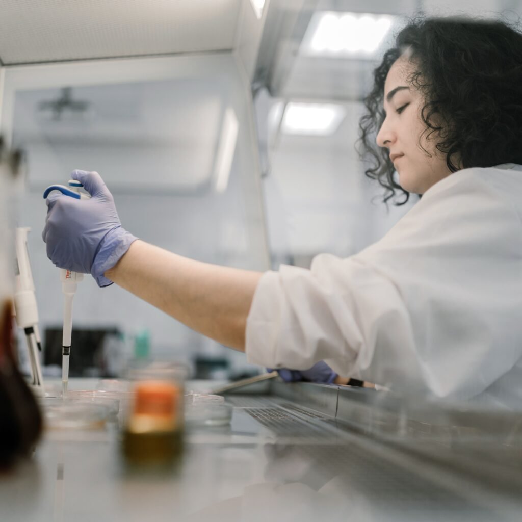Woman in lab coat conducting research with pipette in modern laboratory.
