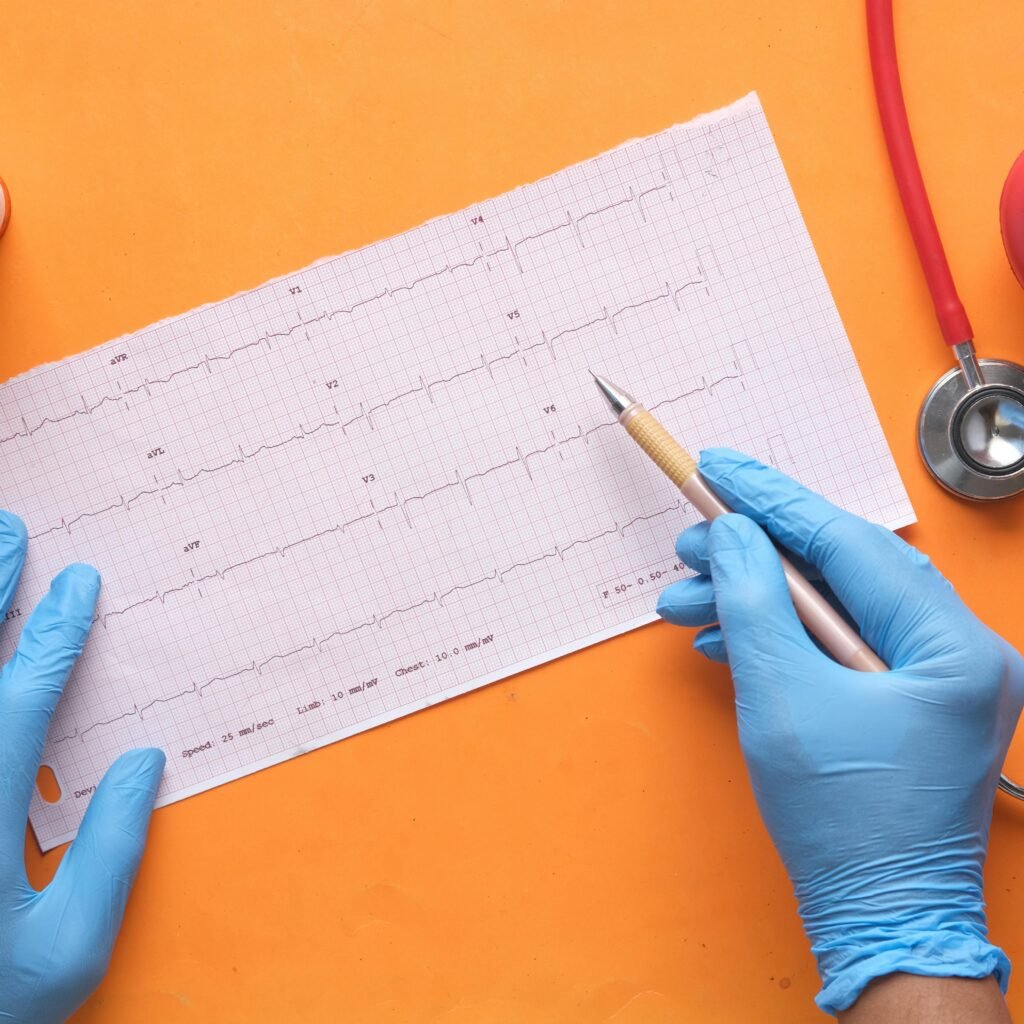Hands with gloves analyzing an electrocardiogram on an orange background with stethoscope and pills.