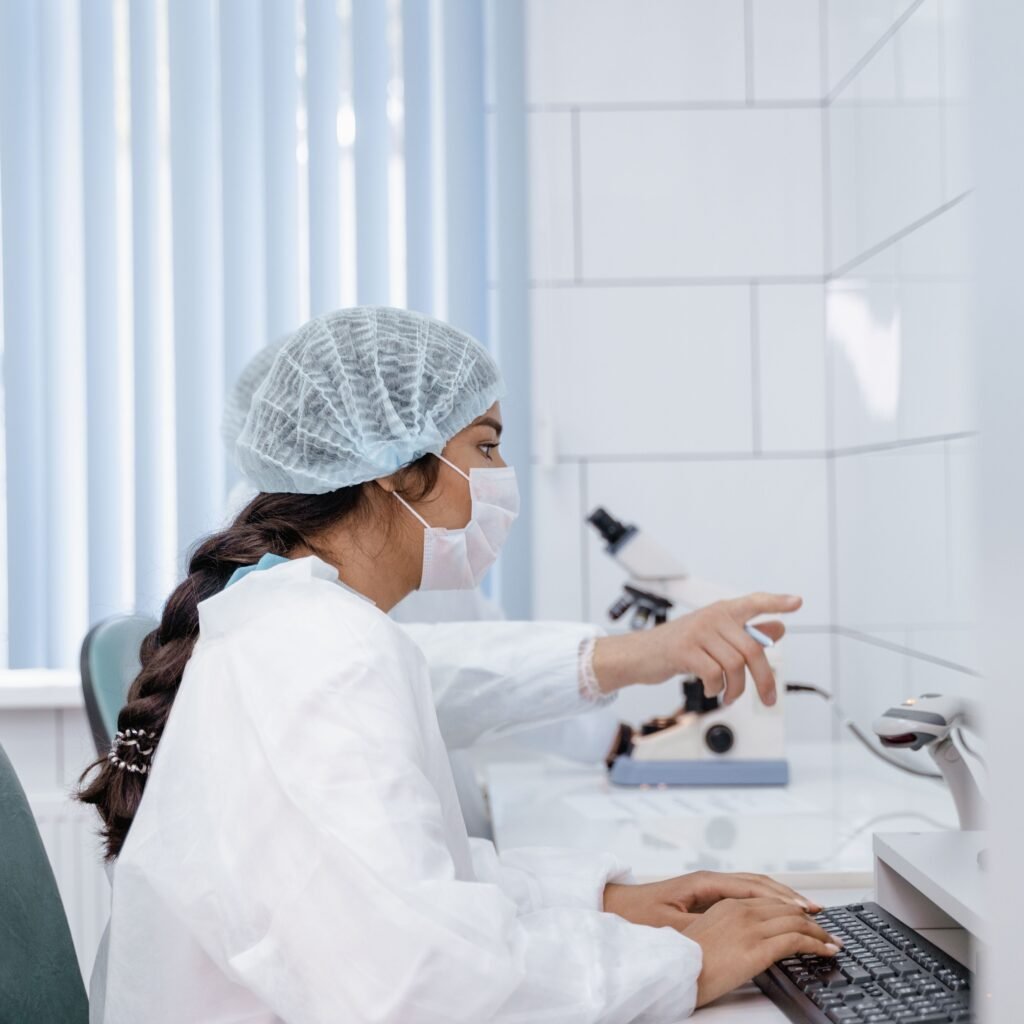 Female scientist in laboratory coat working at computer in a clean, modern lab.